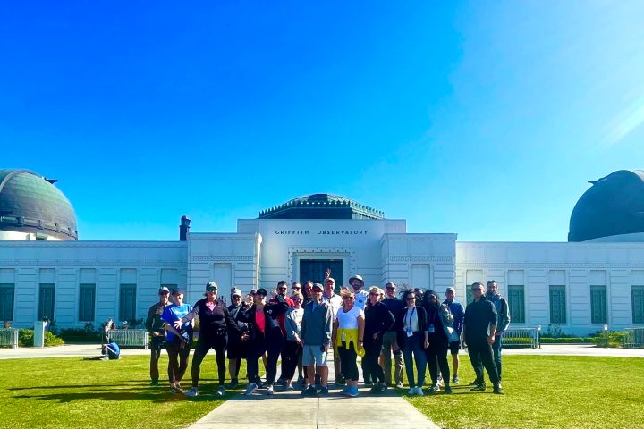a group of people standing in front of the griffith observatory on a private tour