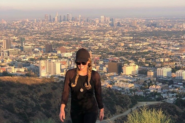 A woman on the Runyon Canyon Trail in West Hollywood, California with a view of Los Angeles in the background