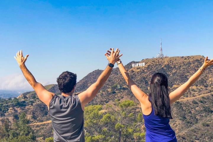 two people holding hands by the hollywood sign in griffith park