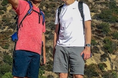 Two hikers below the Hollywood Sign one points out directions
