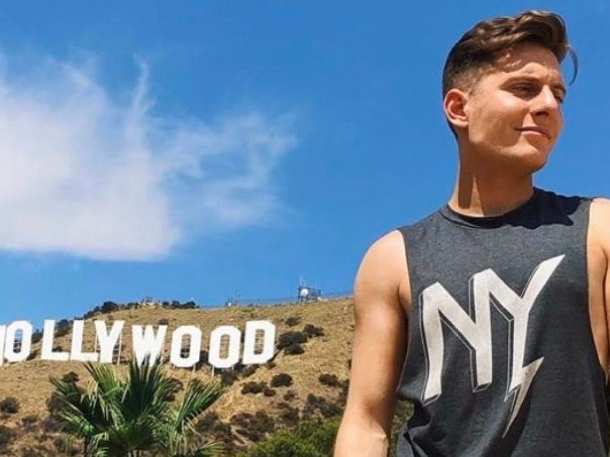 young man standing under the hollywood sign in Los angeles