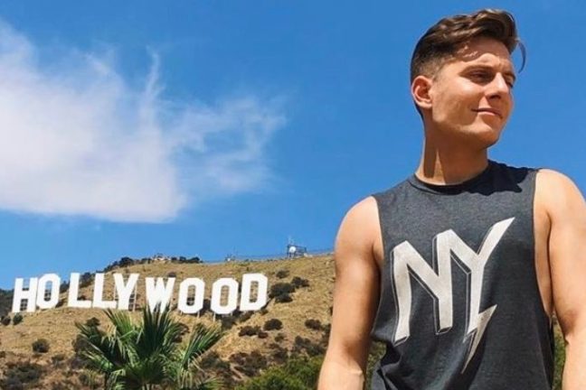 young man standing under the hollywood sign in Los angeles