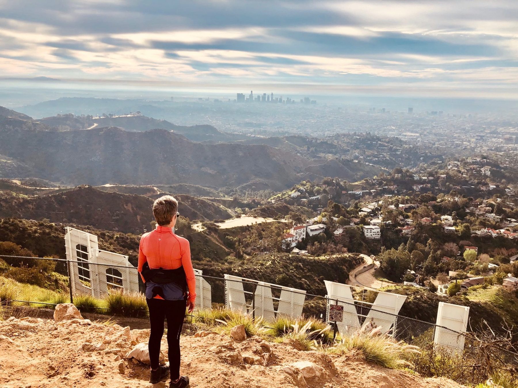 a hiker standing behind the hollywood sign on a hollywood sign tour