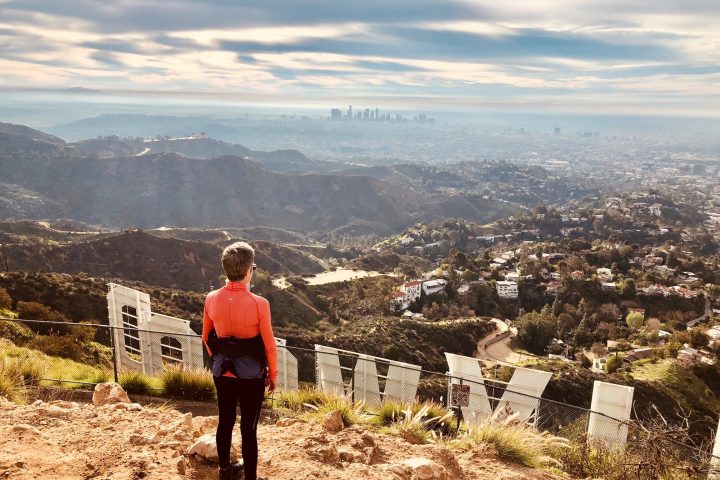 a hiker standing behind the hollywood sign on a hollywood sign tour