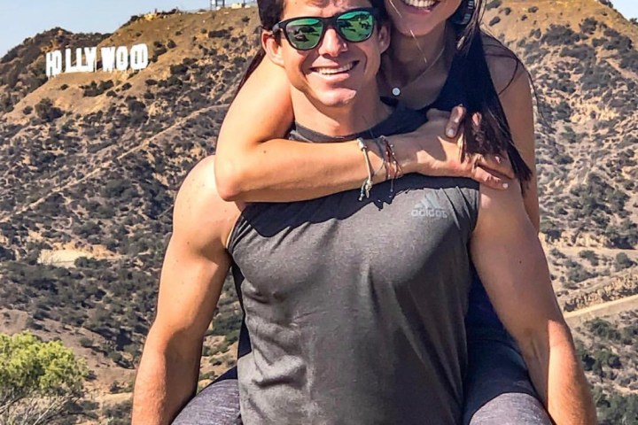 a couple standing in front of the hollywood sign on a hike