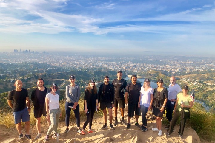 group of hikers standing on the hill behind the hollywood sign