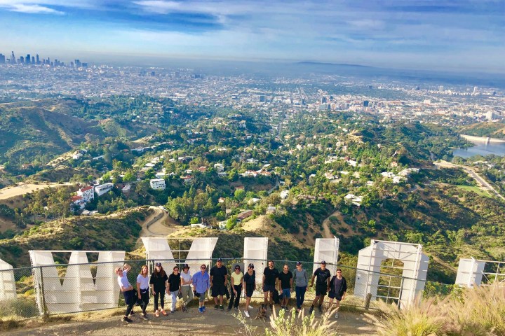a group of people standing behind the hollywood sign