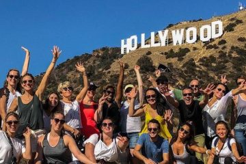 a group of people beneath the hollywood sign