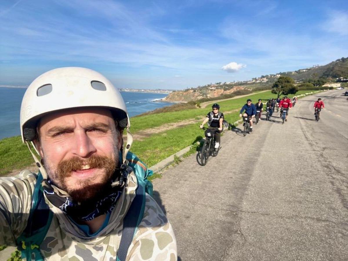 a man wearing a helmet riding a motorcycle down a dirt road