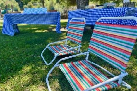 a couple of lawn chairs sitting on top of a grass covered field