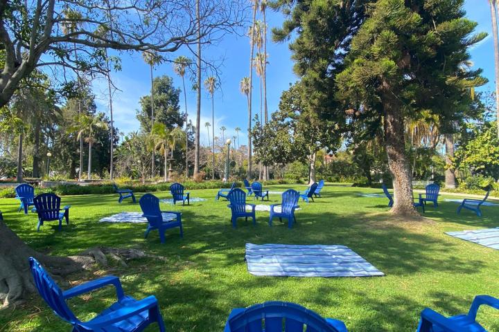 a group of people flying a kite in a blue chair in a park
