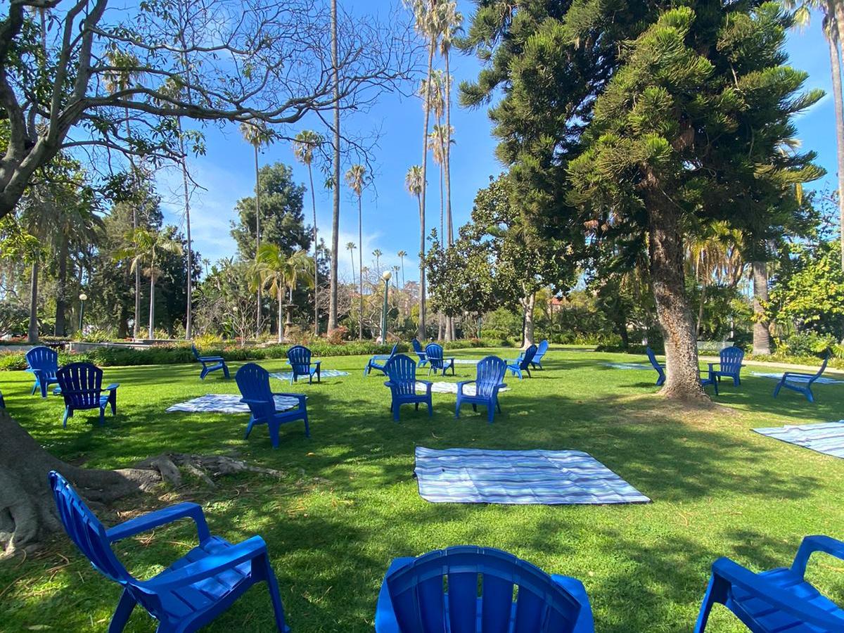 a group of people flying a kite in a blue chair in a park