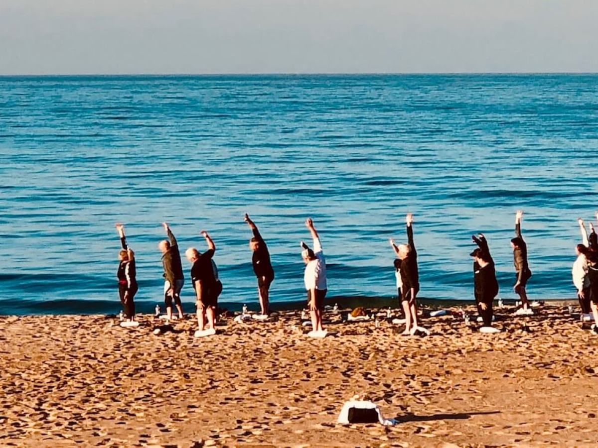 group doing yoga on beach