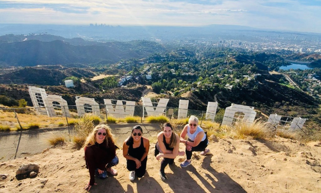 four people hiking behind the hollywood sign