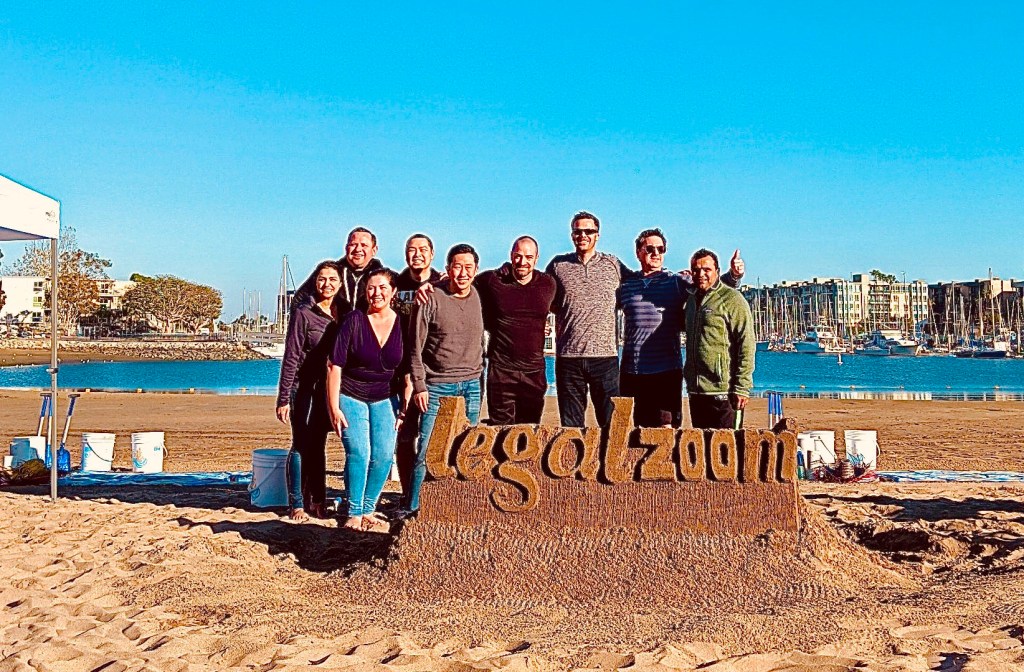 a group of people standing on top of a sandy beach with Cadillac Ranch in the background