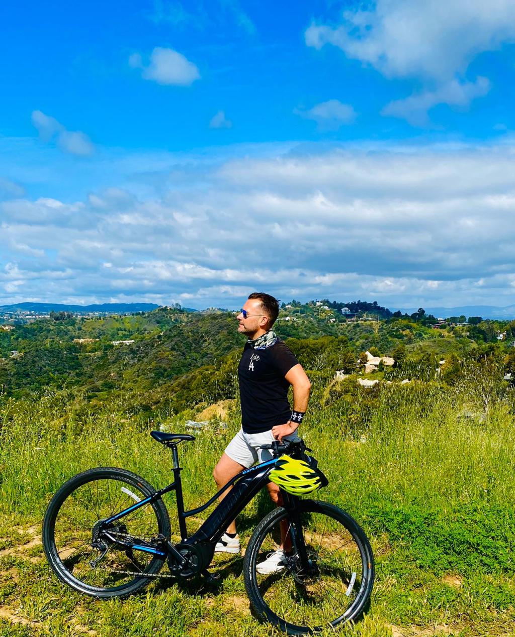 a man with a bicycle in front of a green field