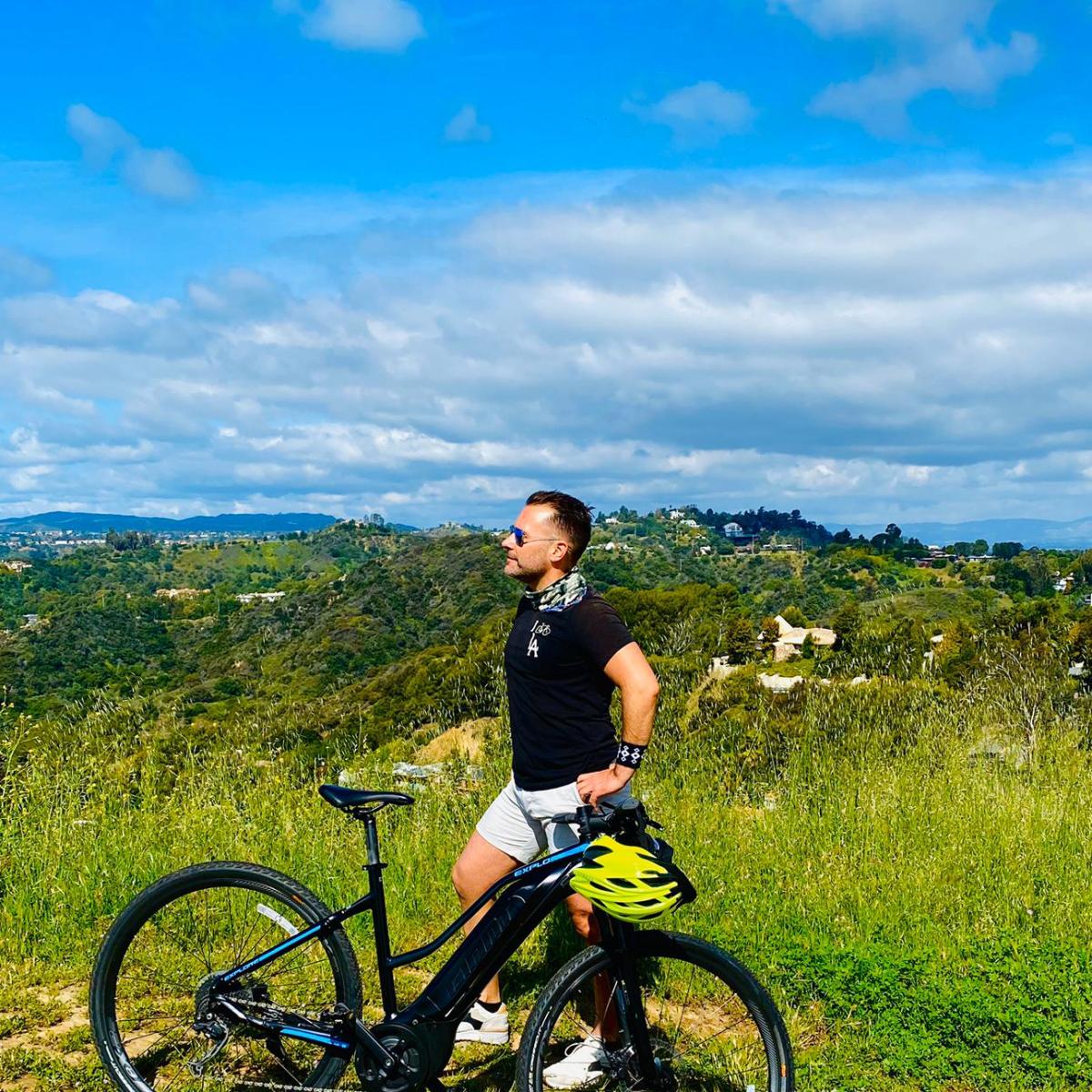 a man with a bicycle in front of a green field