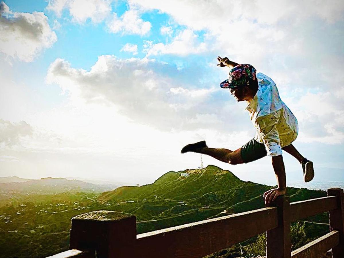 a person jumping on a fence by the hollywood sign