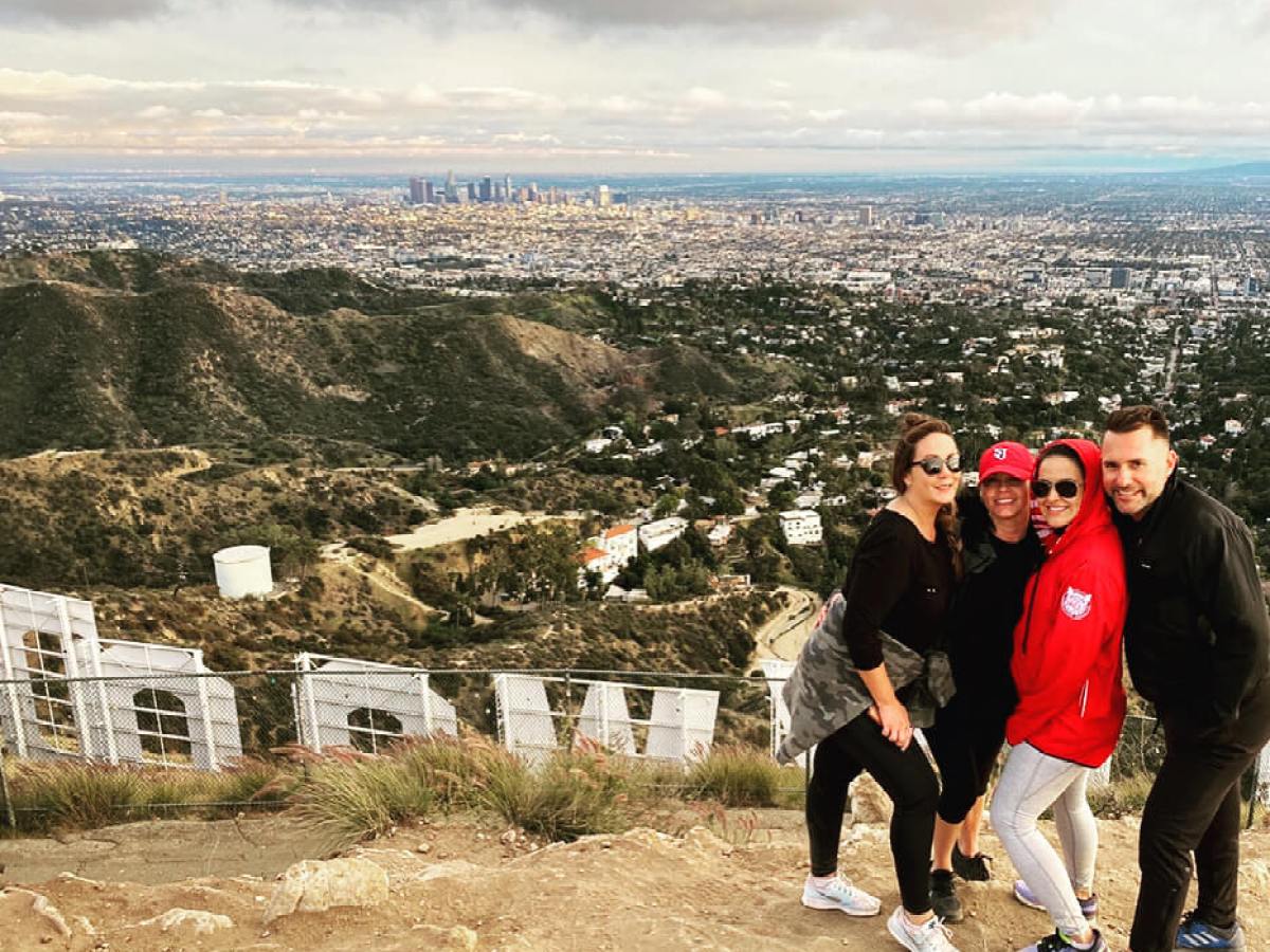 a group of people standing behind the hollywood sign on a hollywood sign hike
