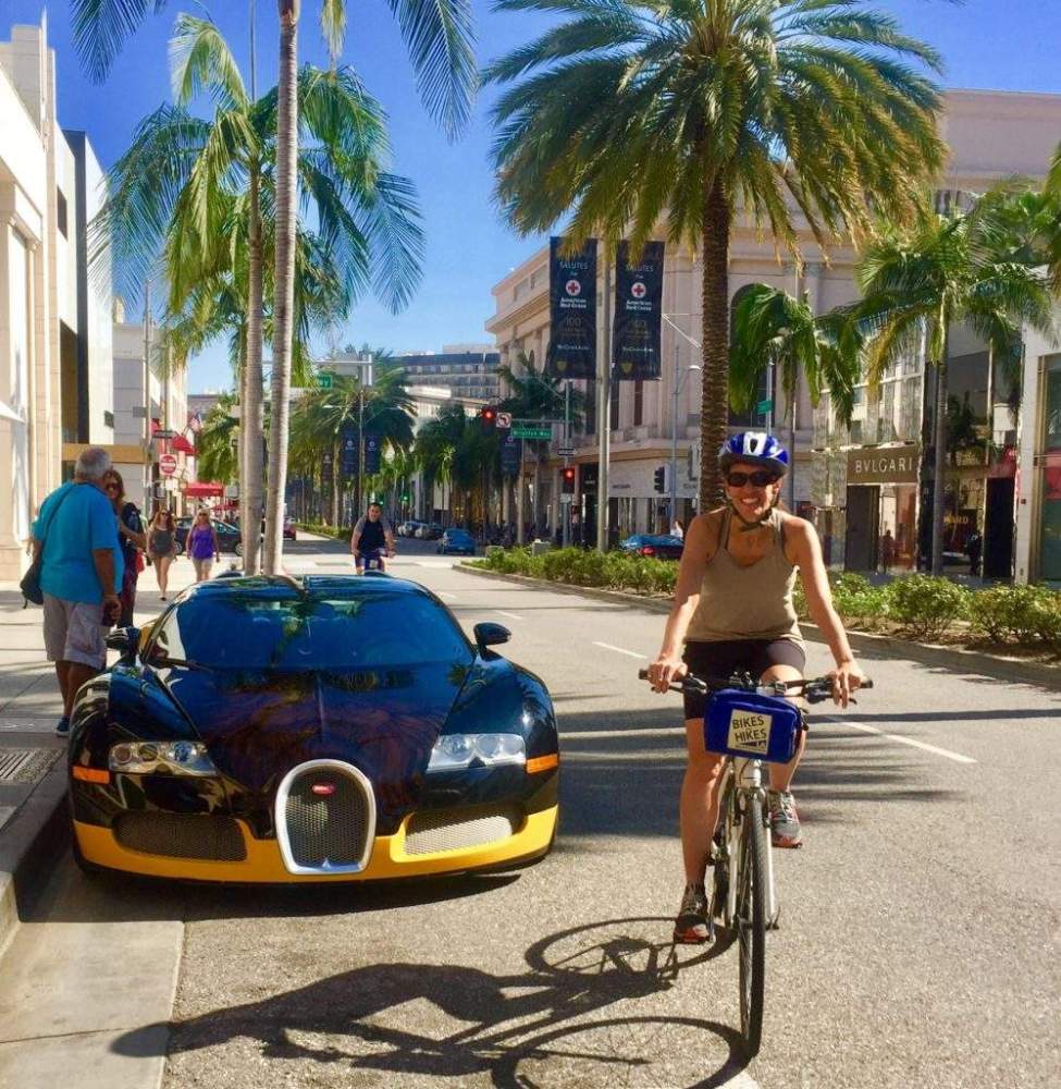 a group of people riding bikes down a street next to a palm tree