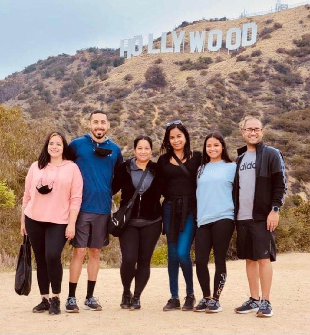 a group of people posing for a photo below the hollywood sign