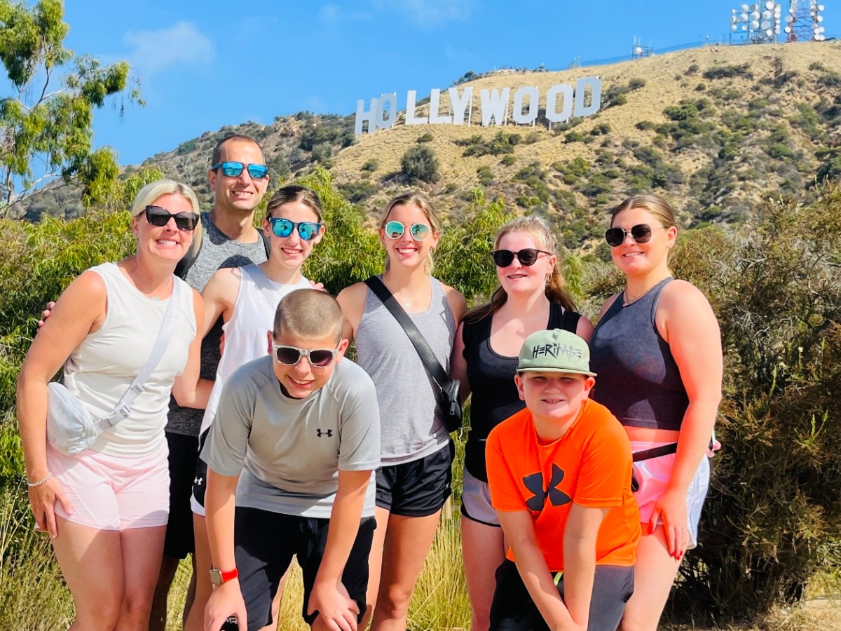 a group of people posing below the hollywood sign