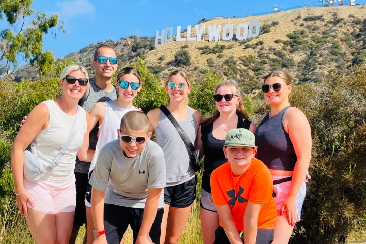 a group of people posing below the hollywood sign
