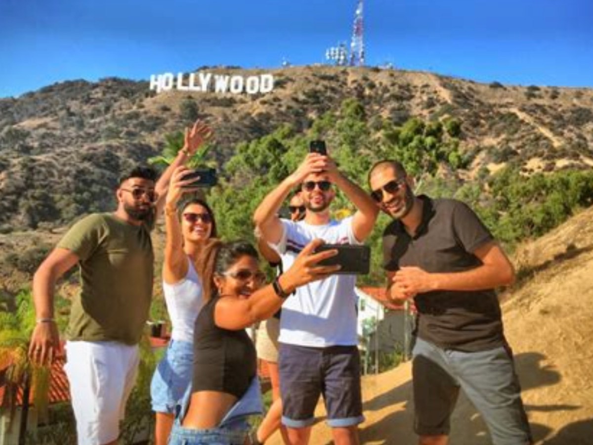 a group of people posing for the camera on a hollywood sign hike tour