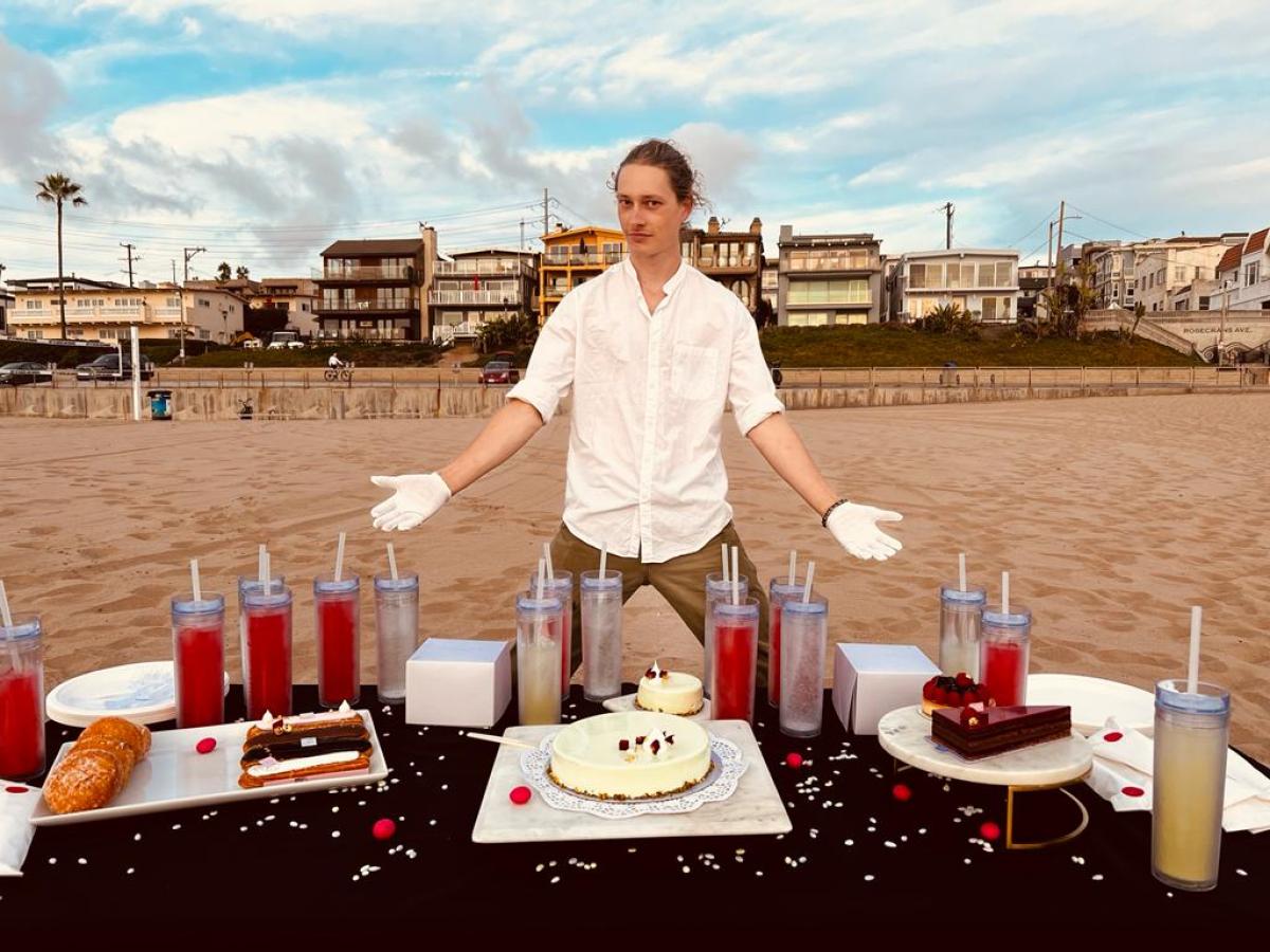 a man standing behind a table with cakes