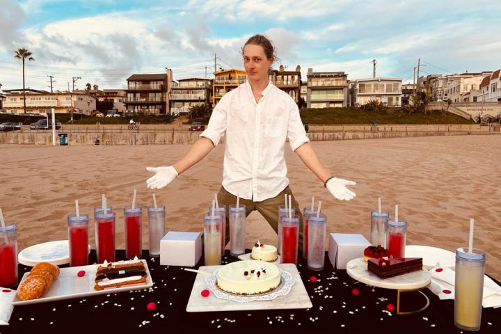 a man standing behind a table with cakes