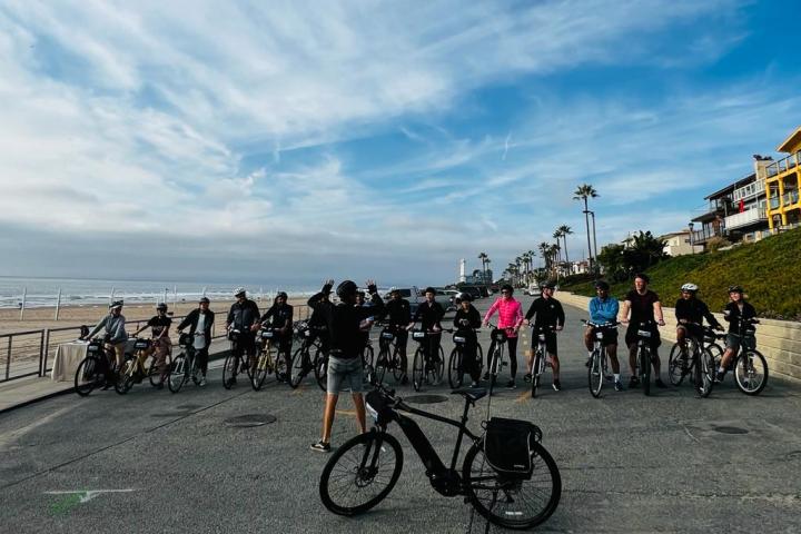 a group of people riding on bikes on the boardwalk near the ocean
