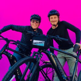 two people on bicycles next to the pink wall melrose