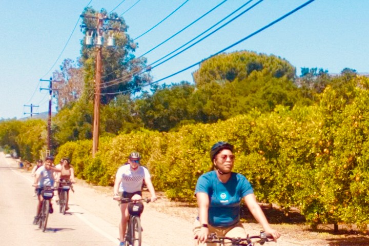 a group of people riding on the back of a bicycle on a street on an ojai tour