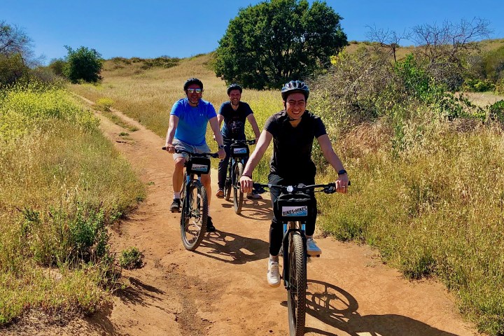 three people riding bikes on a group mountain bike tour