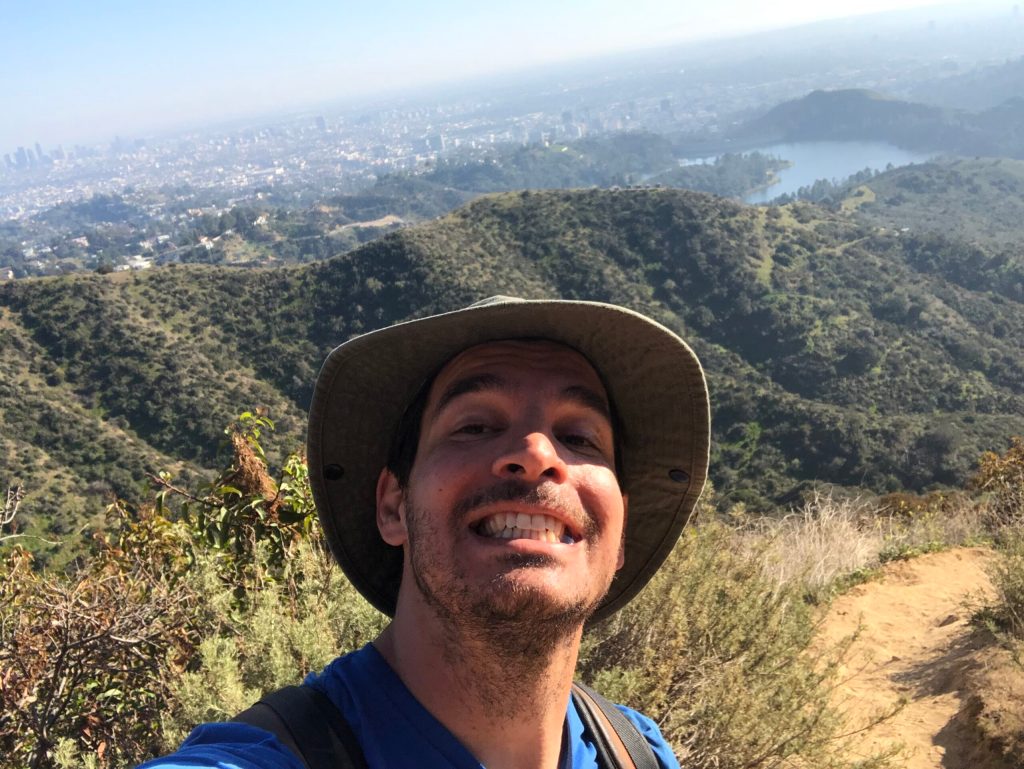 a man wearing a hat and a mountain in the background
