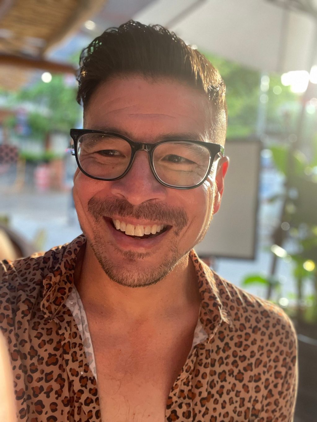 a man wearing glasses and smiling at the camera