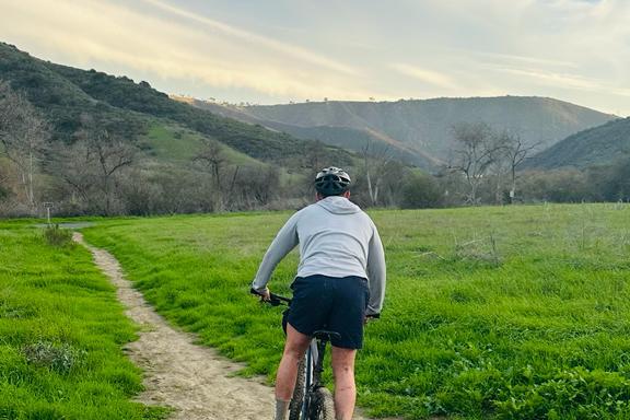 a man riding a bike down a dirt road in orange county