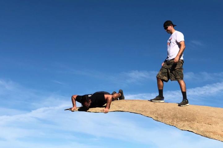 two people on a hike tour of san diego are on a rock, one is standing and one is laying down