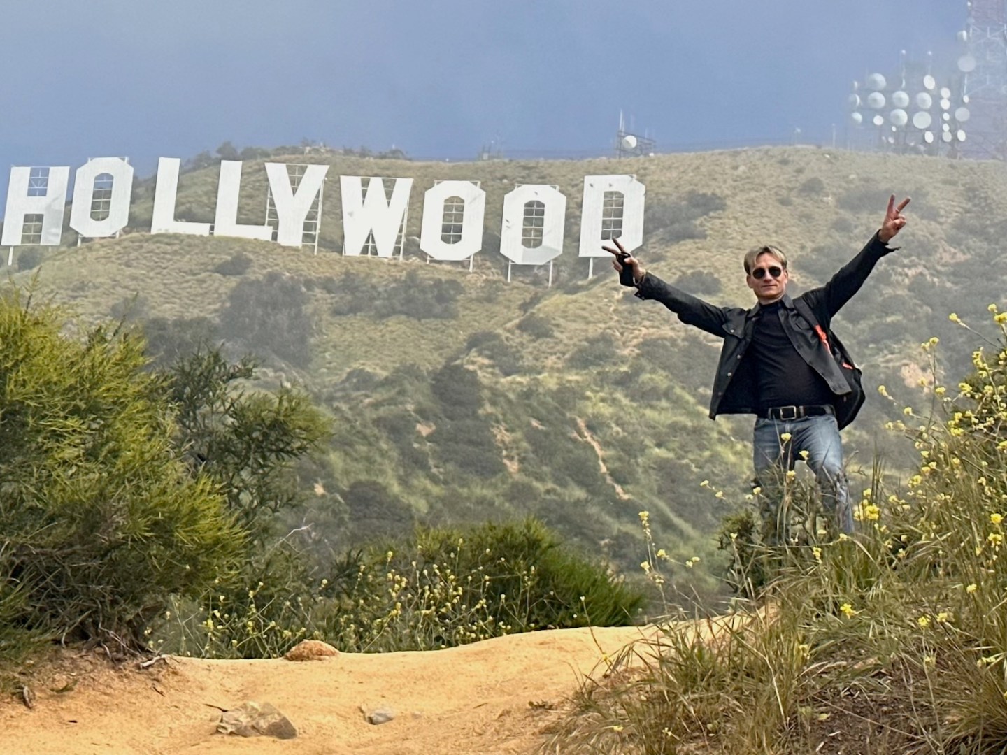 a man posing below the hollywood sign