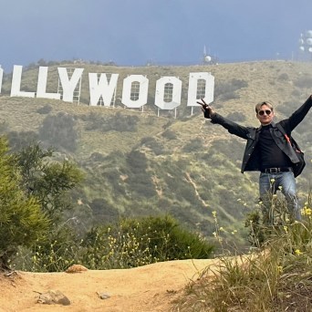 a man posing below the hollywood sign