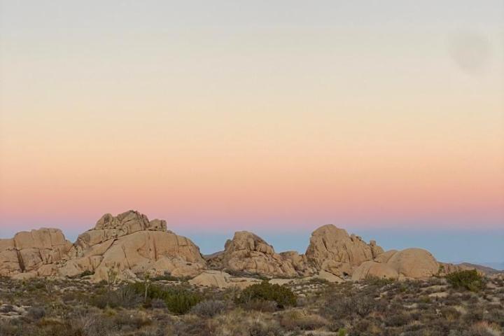 a group of rock formations underneath a moon and sky in joshua tree