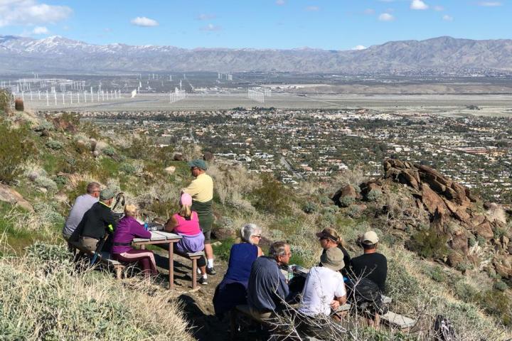 a group of people sitting on a mountain having a picnic on a palm springs hike tour