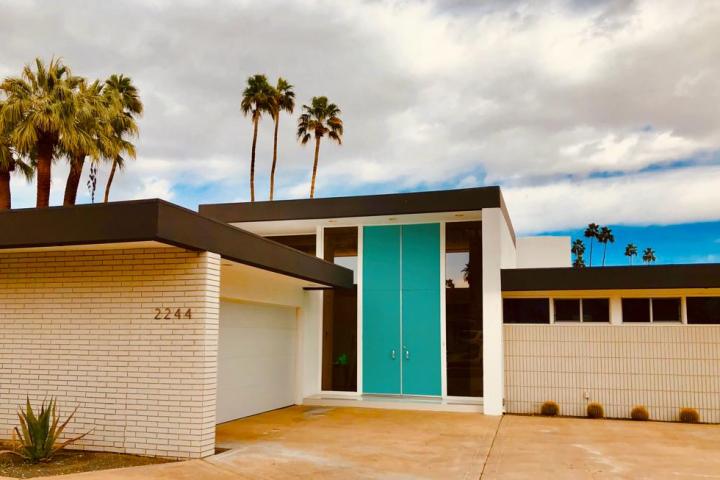 a white and blue and brown house with palm trees in the background