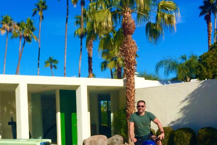 a man riding a bicycle in front of a palm tree