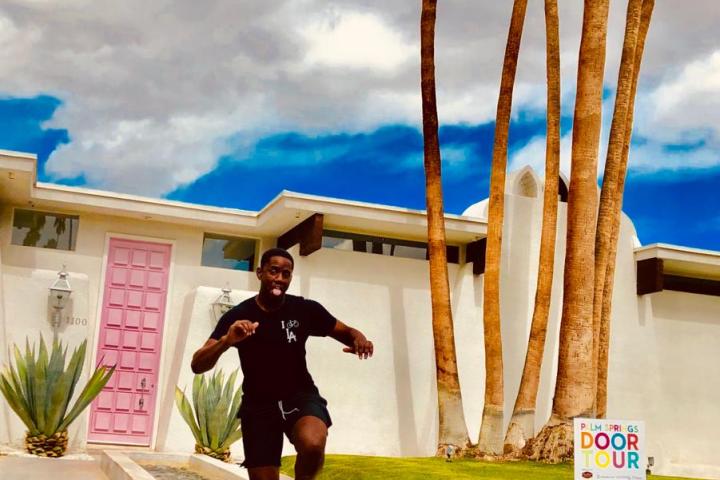 a person jumping up in the air in front of a white and pink house in palm springs
