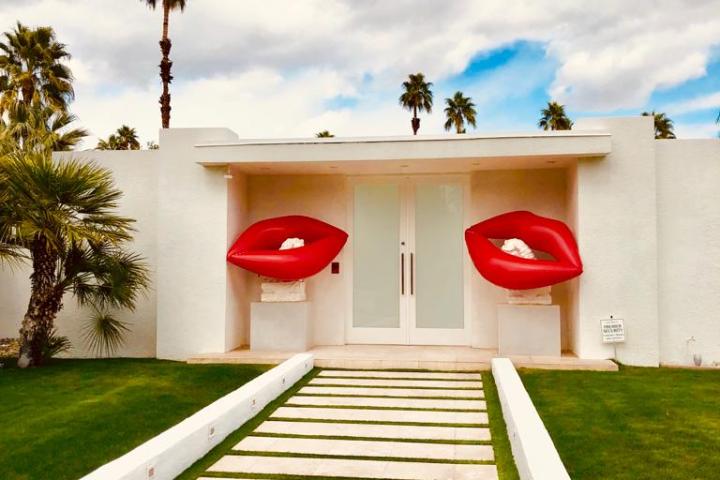 a white house in palm springs with red lips outside of the doors