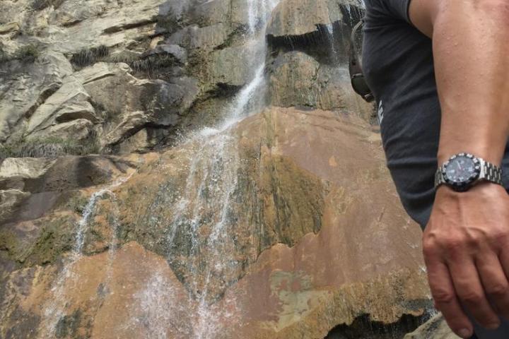 a person standing below a waterfall on a santa barbara group tour