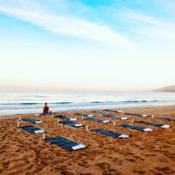 a group of people doing yoga on a beach