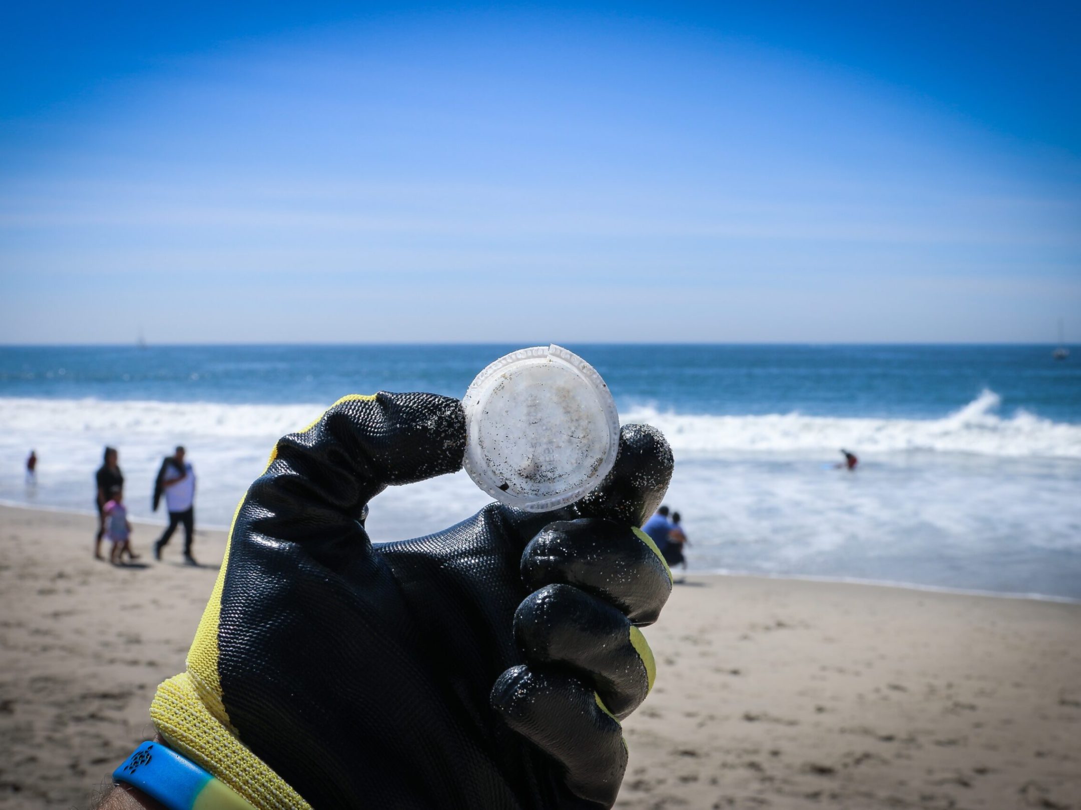 a group of people standing on top of a sandy beach doing a beach clean up