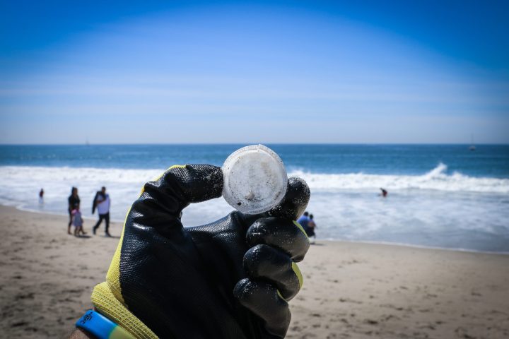 a group of people standing on top of a sandy beach doing a beach clean up